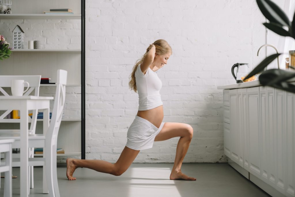 side view of pregnant woman doing fitness exercises at home